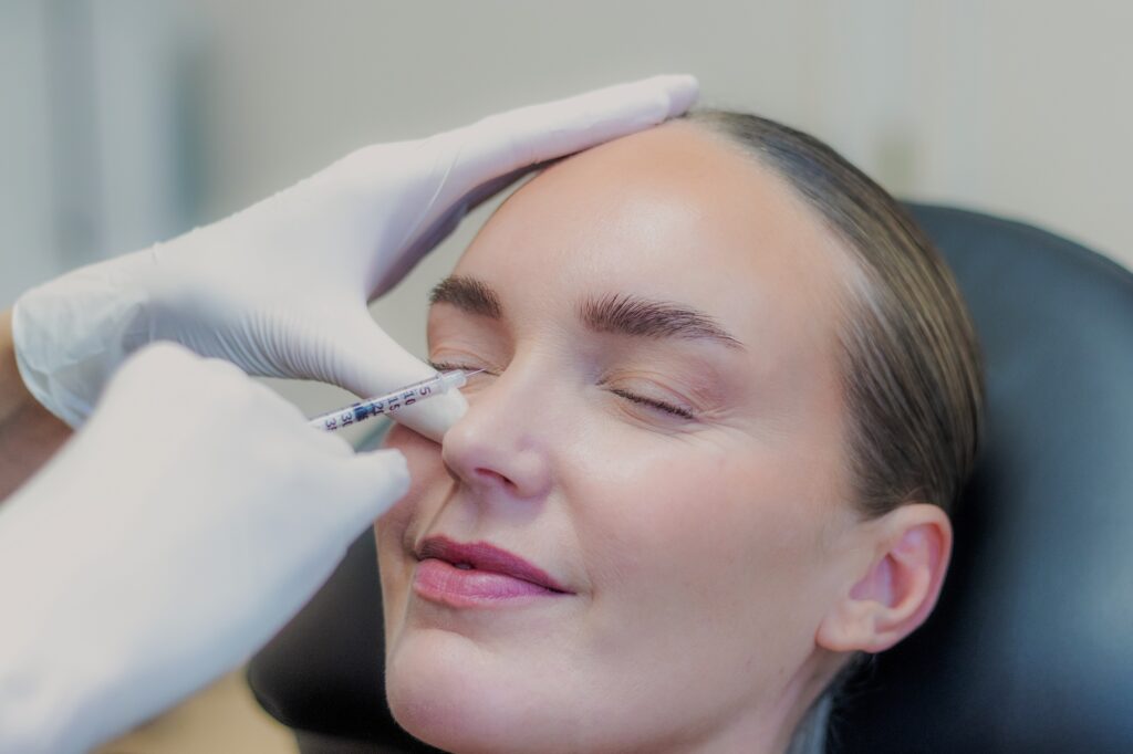 Behandler giver botox på siden af næsen mod rynker ved næseryggen, kvinden ligger afslappet i behandlingsstolen