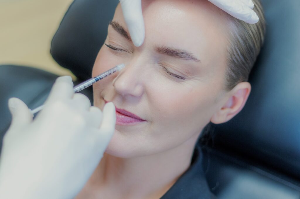 Behandler giver botox på siden af næsen mod rynker ved næseryggen, kvinden ligger afslappet i behandlingsstolen